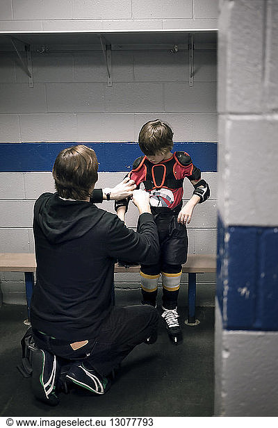 Vater hilft Sohn mit Eishockey-Trikot