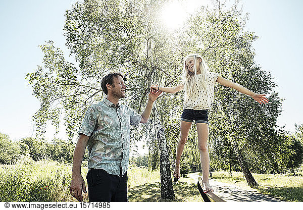 Vater hilft Tochter beim Balancieren auf einer Parkbank