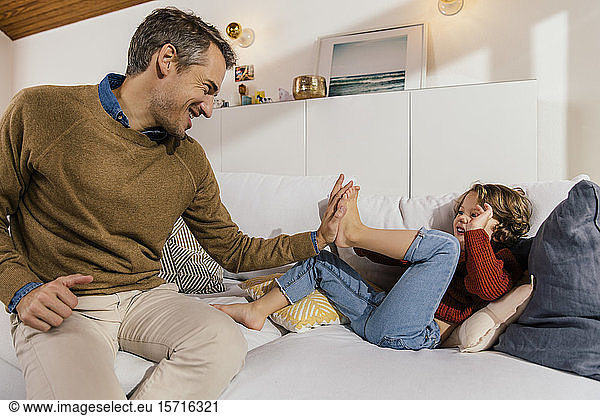 Vater kämpft mit Tochter auf dem Sofa