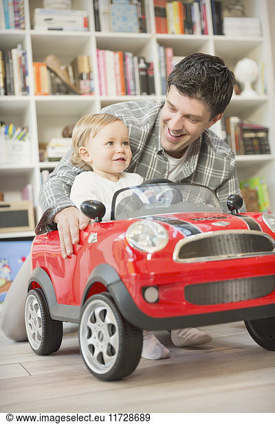 Vater schiebt Baby-Sohn im Spielzeugauto