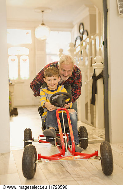 Vater schiebt Sohn auf Spielzeugauto im Foyerflur