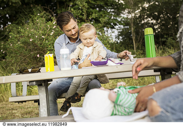 Vater sitzt mit Sohn (18-23 Monate) am Picknicktisch
