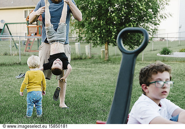 Vater und Jungen spielen im Sommer in einem vorstädtischen Hinterhof.