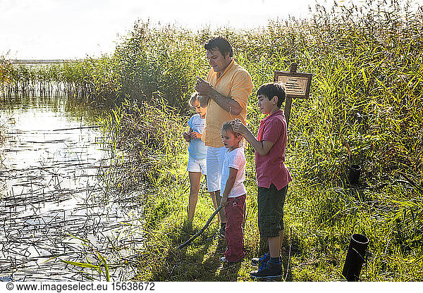 Vater und Kinder stehen am Wasserlauf  Darß  Mecklenburg-Vorpommern  Deutschland