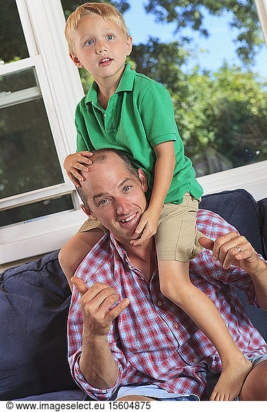 Vater und Sohn mit Hörbehinderung gebärden play in amerikanischer Zeichensprache auf ihrer Couch