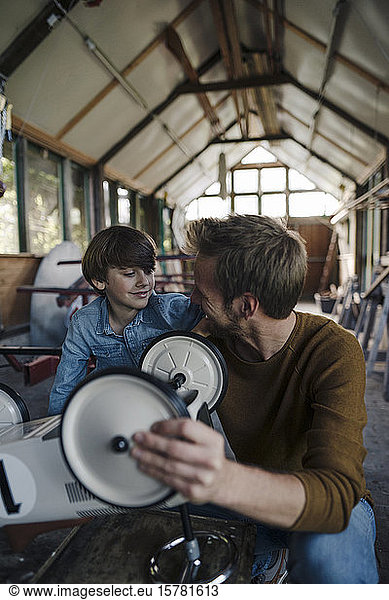 Vater und Sohn reparieren Spielzeugauto in der Scheune