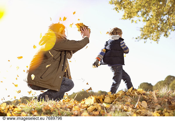 Vater und Sohn spielen im Herbstlaub