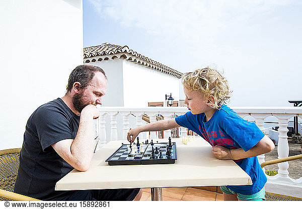 Vater und Sohn spielen Schach auf der Dachterrasse  Spanien