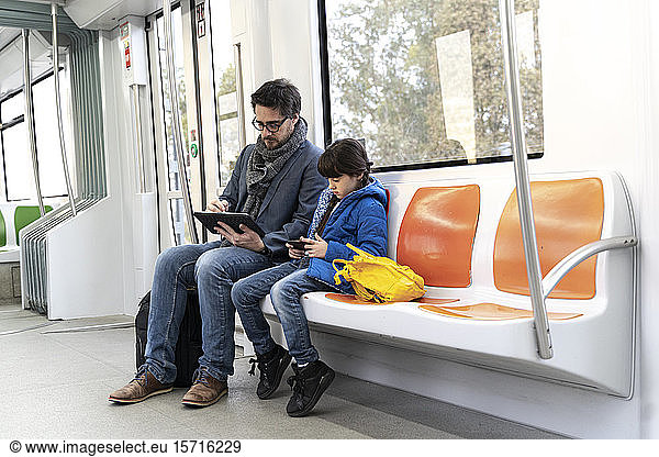 Vater und Tochter in der U-Bahn und mit Tablet und Smartphone