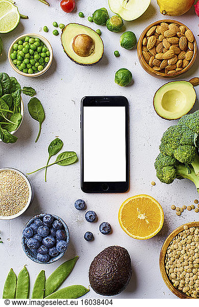 Vegetables  fruit  lentils and almonds arranged around a smartphone