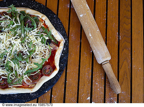 Vegetarian and vegetable pizza next to a wooden rolling pin.