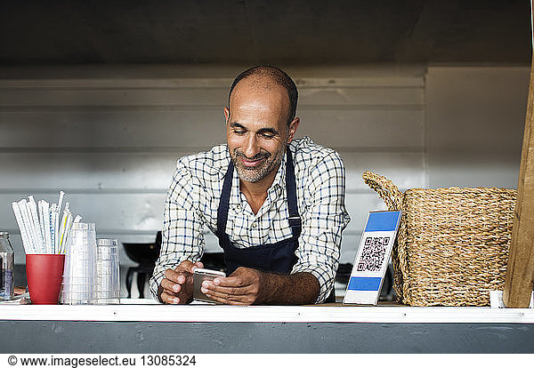 Vendor using smart phone while standing in food truck