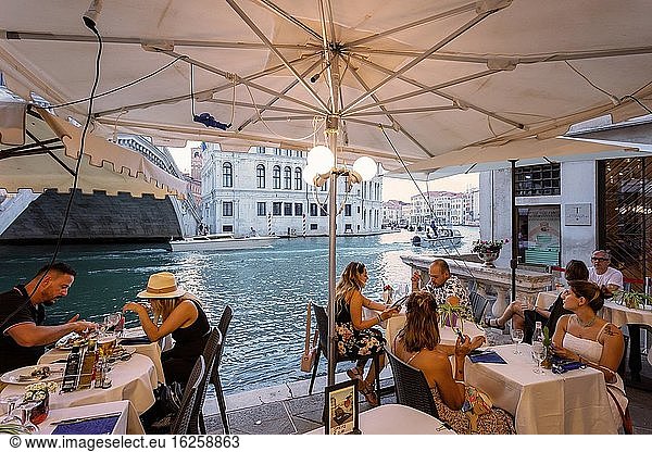 Venedig  Italien - 1. August 2020: Touristen essen an den Tischen eines Restaurants in der Nähe des Canal Grande zu Abend.