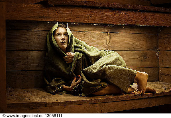 Verängstigte Frau mit Decke eingewickelt in der Sauna