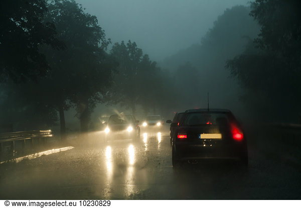 Verkehr auf der Kreisstraße bei Regen in der Dämmerung