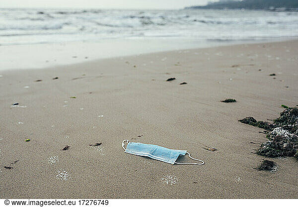 Verlassene Gesichtsmaske am Strand