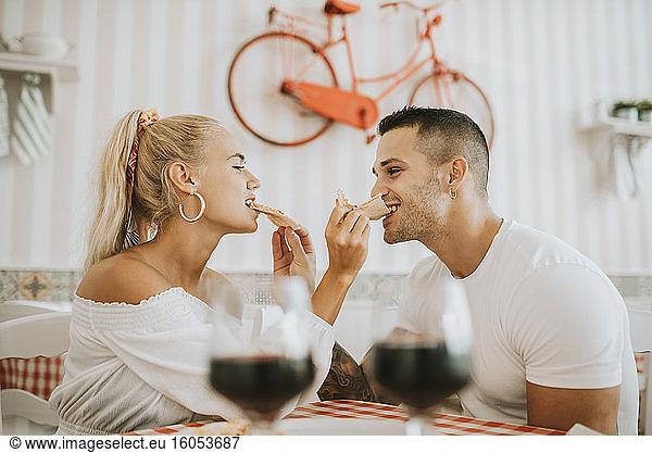 Verliebtes junges Paar  das sich im Restaurant gegenseitig mit Pizza füttert