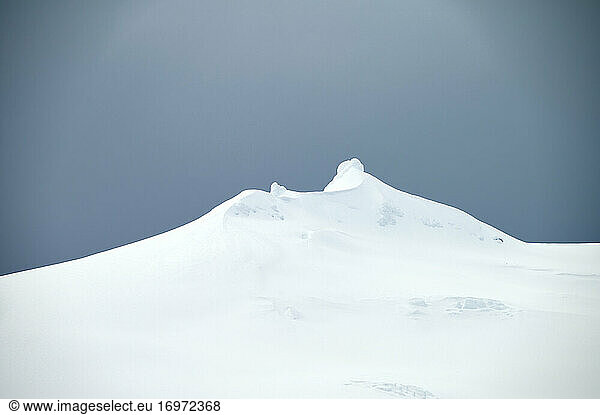 Verschneiter Hügel gegen blauen Himmel