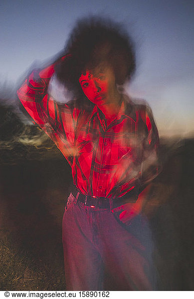 Verschwommene junge Frau mit Afro-Frisur nachts im Freien