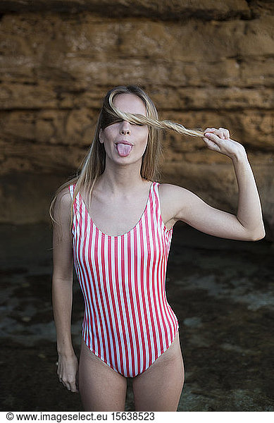 Verspielte junge Frau im rot-weiß gestreiften Badeanzug