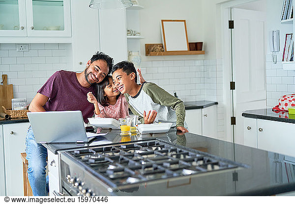 Verspielter Vater und Kinder essen und Laptop in der Küche benutzen