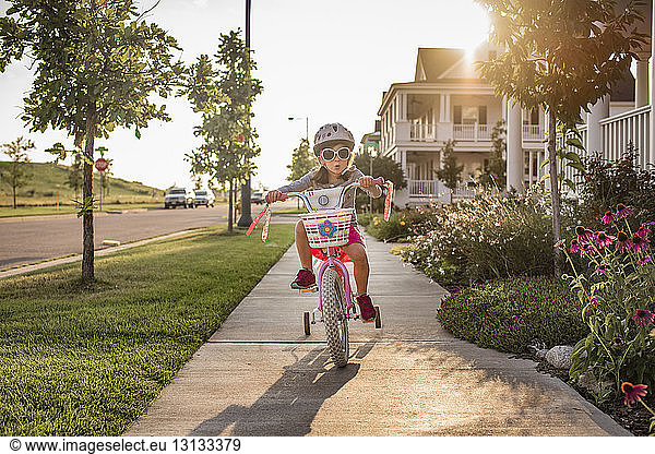 Verspieltes Mädchen mit Sonnenbrille beim Fahrradfahren