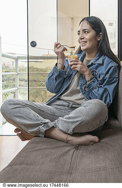 Vertical photo of a smiling woman eating homemade cashew butter
