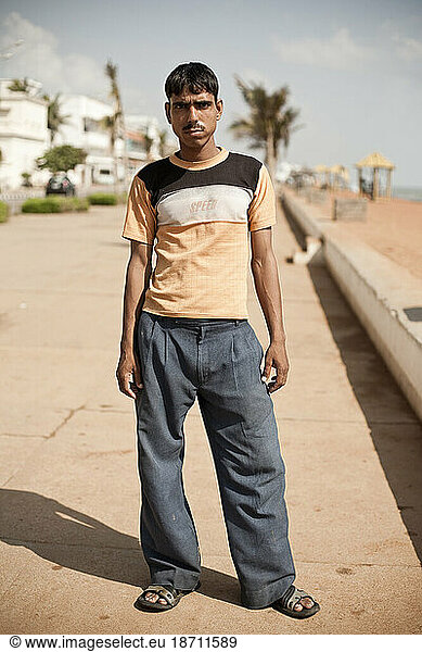 Vertical portrait of a young man on a boardwalk.