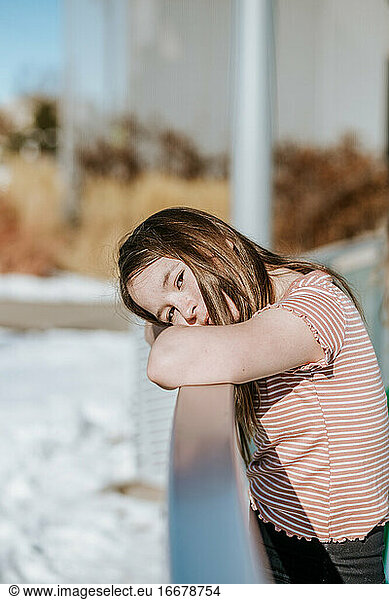 vertical portrait of preteen resting head on the side of ice rink