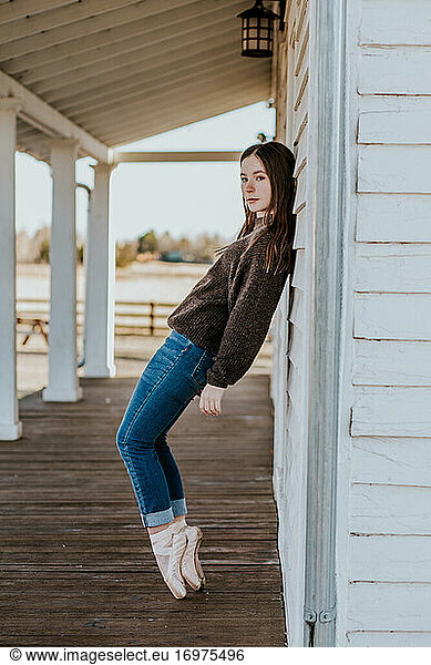 Vertical portrait of teen girl leaning against wall in pointe shoes