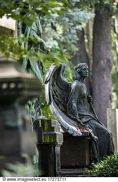 Verwitterte Engelsstatue am Rande eines Grabes auf dem Friedhof