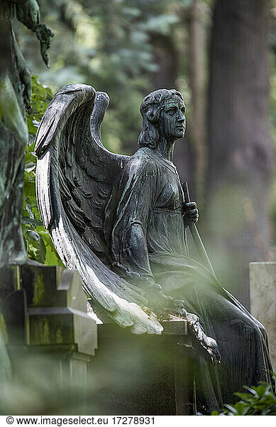 Verwitterte Engelsstatue am Rande eines Grabes auf dem Friedhof
