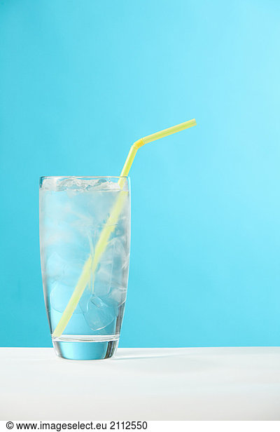 Very full glass of water with ice and yellow drinking straw