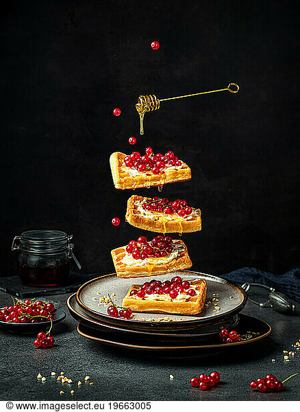 Viennese waffles with berries and honey on black. Levitation concept.