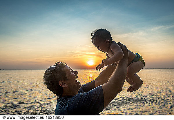 Vietnam  Phu Quoc island  Ong Lang beach  Father holding baby in beach at sunset