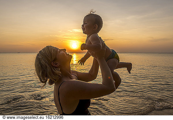 Vietnam  Phu Quoc island  Ong Lang beach  Mother holding baby in beach at sunset