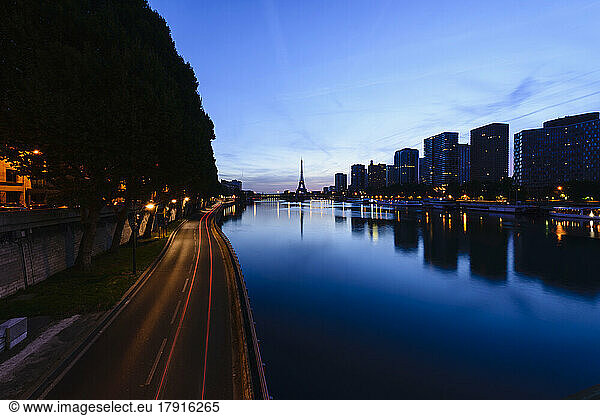 View along the River Seine to the Eiffel tower  the river embankment  and the city at dusk  reflections on the water.