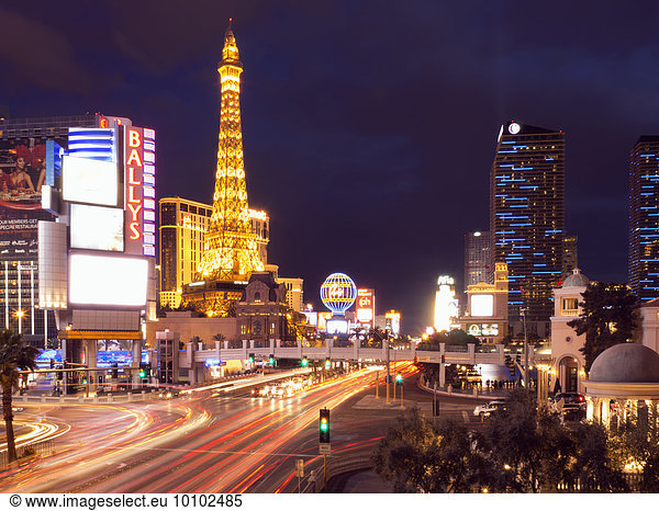 View along the Strip in Las Vegas at night  with the illuminated Paris Las Vegas Hotel and Casino in the background.