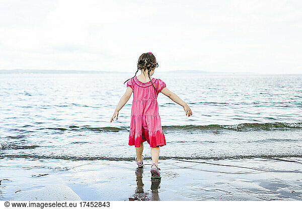 View from behind of a young girl on a sandy beach