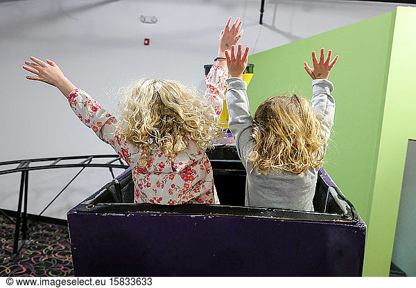 view from behind of two girls with hands up on rollercoaster