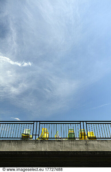 View from below of yellow and blue chairs on a terrace.