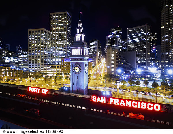 View from the air of the Ferry Building in San Francisco  at night. The city buildings of downtown and the waterfront buildings.