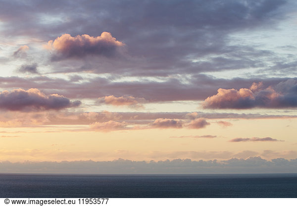 View from the land over the ocean  to the horizon. Sunset light shining on the clouds.