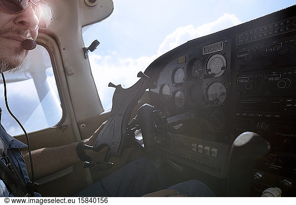 View inside the cockpit of a small airplane with pilot looking off