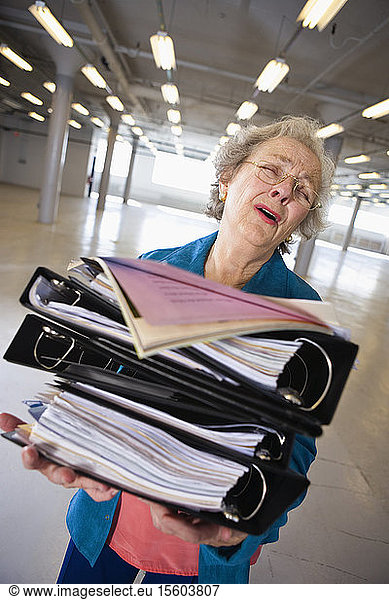 View of a senior woman carrying heavy files.