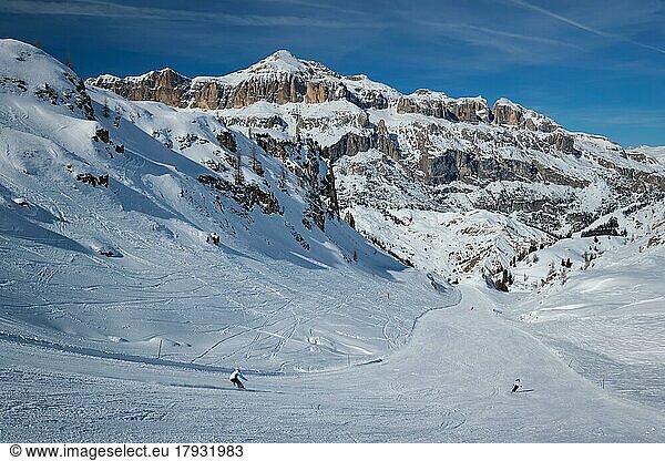 View of a ski resort piste with people skiing in Dolomites in Italy. Ski area Arabba. Arabba  Italy  Europe
