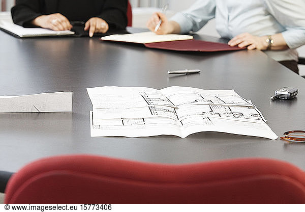 View of business women sitting with blueprints on the table.