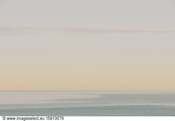 View of calm ocean waters  horizon and sky at dawn