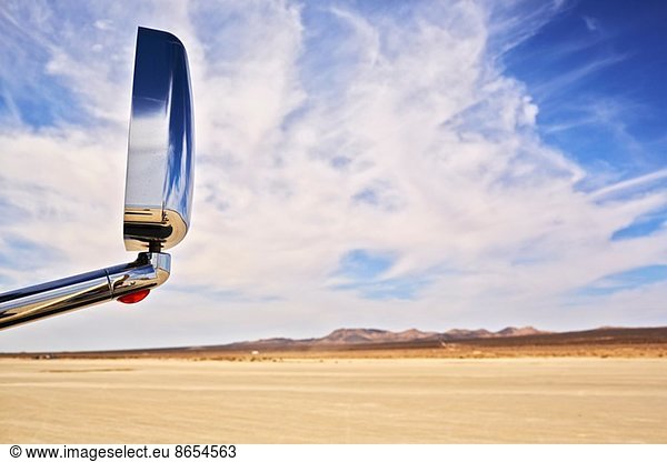 View of car wing mirror and arid landscape