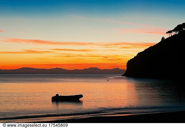 View of dinghy in small bay of Elba just after sunset  on the horizon silhouette of mountain range of French island Corsica  Morcone  Elba  Tuscany  Italy  Europe